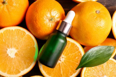 Bir şişe portakal yağı ve ahşap arka planda taze meyveler. Yakın plan.