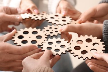 Tahta dişlileri tutan bir grup insan.