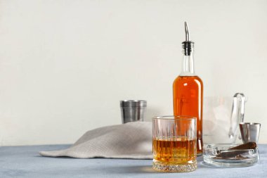 Bir bardak soğuk rom, şişe ve kül tablası. Masada beyaz arka planda puro var. Yakın çekim.