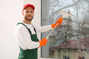 Odada cam sileceği olan bir erkek işçi.