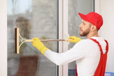 Odada cam sileceği olan bir erkek işçi.