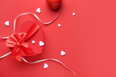 Kırmızı arka planda kupa ve kurdeleli hediye kutusu. Sevgililer Günü kutlaması