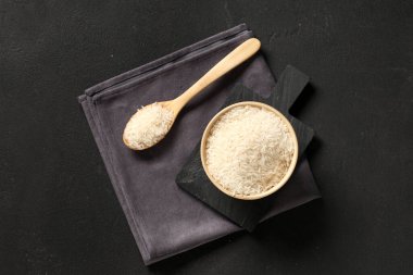 Tahta kase ve kaşık, siyah arka planda çiğ pirinç.