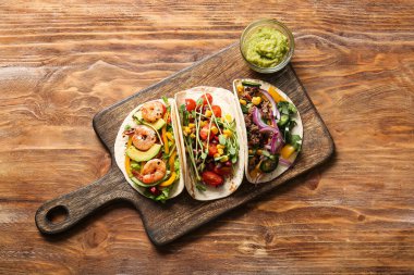 Ahşap zemin üzerinde farklı lezzetli tacolar bulunan tepsi.