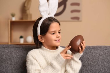 Oturma odasında çikolata yumurtası olan tavşan kulaklı şirin bir kız.
