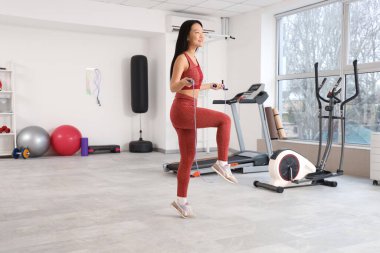 Sportif genç Asyalı kadın spor salonunda ip atlama eğitimi alıyor.