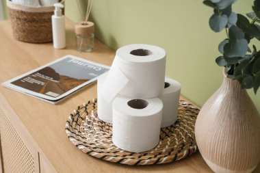 Tuvalet kağıdı ve dergi ruloları yeşil duvarın yanındaki odada.