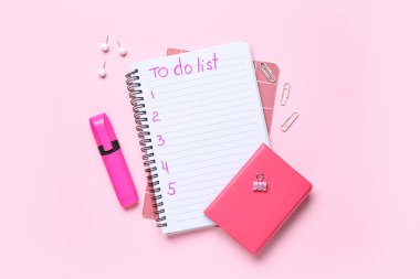 Yapılacaklar listesi boş ve pembe arka planda kırtasiye malzemesi olan bir defter. Üst görünüm