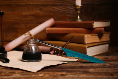 Ahşap zemin üzerinde kalem, mürekkep, makas ve parşömen bulunan eski kitaplar