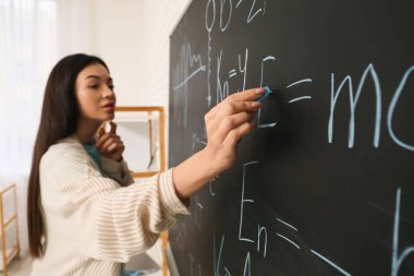 Matematiksel formüller yazan kadın mucit atölyede, yakın planda.
