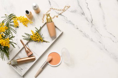 Dekoratif makyaj sehpası, zincir kolye ve beyaz arka planda mimoza çiçekleri.