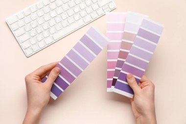 Menekşe rengi palet kumaşlı kadın eller ve bej arka planda klavye. Üst görünüm