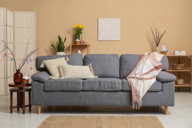 Kanepe, paskalya pastası ve vazoda renkli yumurtalarla dolu şenlikli oturma odasının içi.