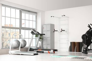 Spor salonunun içinde koşu bantları ve dolap var.