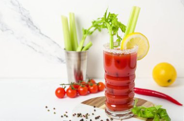 Bir bardak Bloody Mary kokteyli ve beyaz arka planda malzemeler.