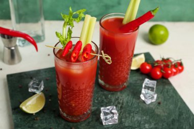 Beyaz masada kırmızı biberli, limonlu ve buzlu Bloody Mary kokteyli.