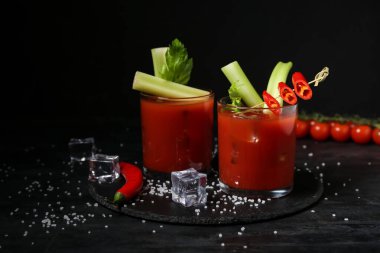 Siyah arka planda kereviz ve kırmızı biberli Bloody Mary kokteyli.