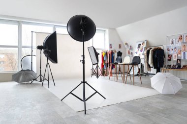 Profesyonel ekipman, tabure ve elbise rafları olan bir fotoğraf stüdyosu.