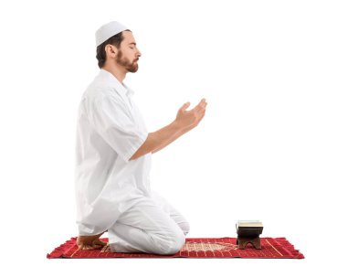 Kuran 'ı okuyan genç Müslüman bir adam beyaz arka plan için dua ediyor. Ramazan kutlaması