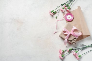 Pembe karanfilli hediye kutuları, ambalaj kağıdı ve bej rengi grunge arka planda kurdele. Uluslararası Kadınlar Günü