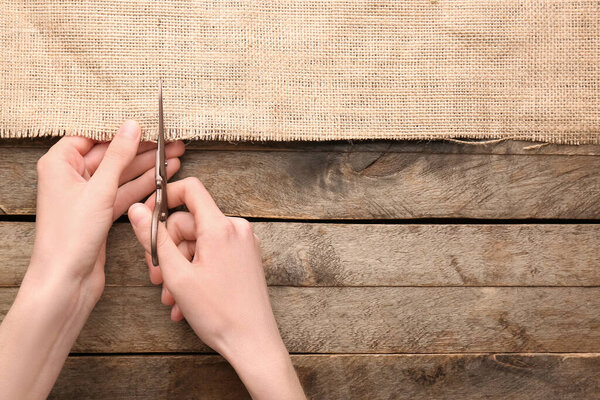 Женщина режет мешковину на деревянном фоне