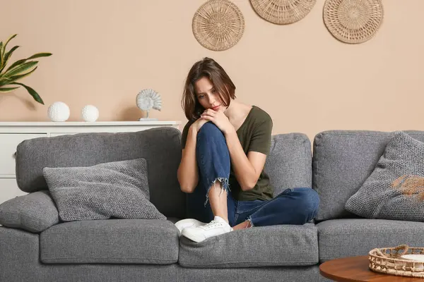 Oturma odasındaki kanepede oturan depresif genç kadın.