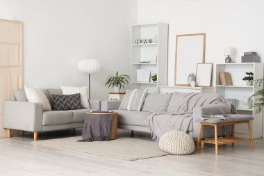 Gri koltukları, yumuşak bankları ve raf üniteleri olan aydınlık oturma odasının içinde.