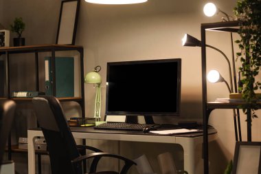 Ofisinde bilgisayar ve parlayan lamba olan işyeri