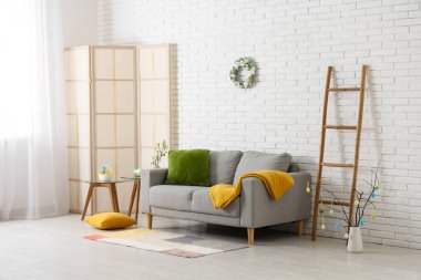 Gri kanepeli ve kahve masasına yumurta boyanmış şenlikli oturma odasının içi. Paskalya kutlaması