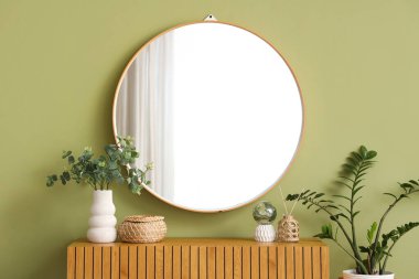 Dekorlu çekmeceler, ev bitkileri ve odadaki yeşil duvardaki ayna. Yakın çekim.