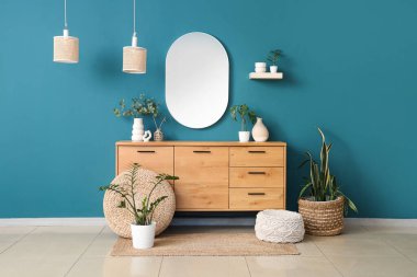 Çekmeceler, ev bitkileri ve mavi duvardaki ayna.