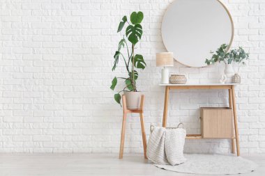 Dekorlu masa, beyaz tuğlalı duvarda ev bitkisi ve ayna.