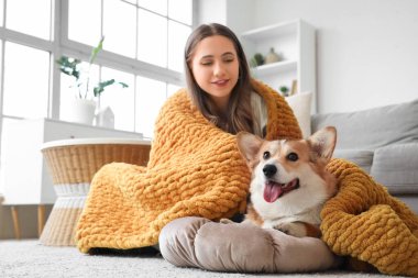 Genç kadın ve Corgi köpeği evde yerde turuncu ekoseli.