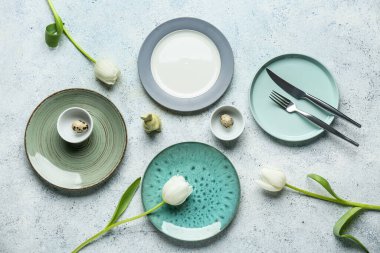 Farklı temiz tabaklar, bıldırcın yumurtaları, oyuncak tavşan ve beyaz arka planda güzel lale çiçekleri. Paskalya kutlaması