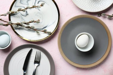 Different clean plates with Easter eggs and pussy willow branches on light pink background