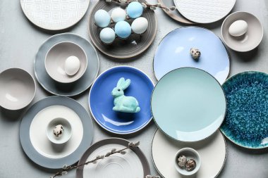 Different clean plates with Easter eggs, toy bunny and pussy willow branches on white background