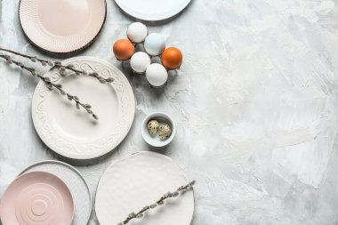 Different clean plates with Easter eggs and pussy willow branches on grey background