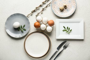 Different clean plates with Easter eggs, fresh leaves and pussy willow branches on white background