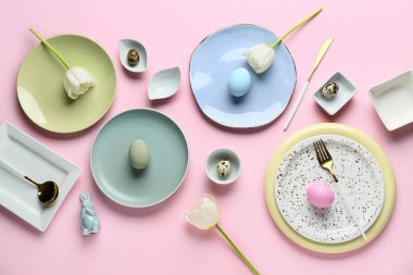 Paskalya yumurtası, oyuncak tavşan ve pembe arka planda güzel lale çiçekleri olan farklı tabaklar.