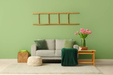 Gri kanepesi ve kahve masasında güzel lale çiçekleri olan şık bir oturma odası.