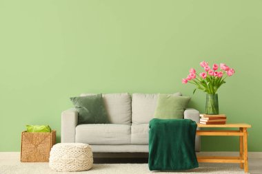 Gri kanepesi ve kahve masasında güzel lale çiçekleri olan şık bir oturma odası.