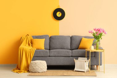 Gri kanepesi ve kahve masasında güzel lale çiçekleri olan şık bir oturma odası.