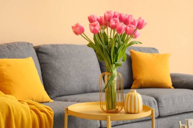 İçinde güzel lale çiçekleri olan bir vazo ve oturma odasındaki sehpanın üzerinde kitaplar, yakın plan.