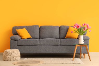 Gri kanepesi ve kahve masasında güzel lale çiçekleri olan şık bir oturma odası.