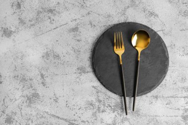 Gri zemin üzerinde çatal ve altın kaşık olan tahta