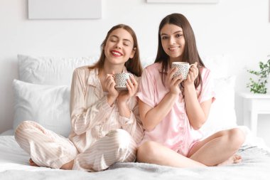 Yatak odasında kahve içen bayan arkadaşlar.