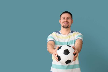 Mavi arka planda futbol topu olan adam.