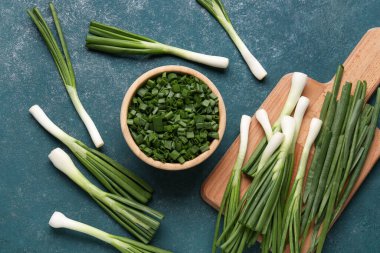 Bir kase dilimlenmiş ve üzerinde taze yeşil soğan ve mavi arka plan.