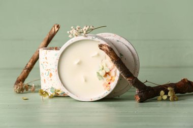 Yeşil ahşap arka planda mumları ve ağaç dalları olan tutucular