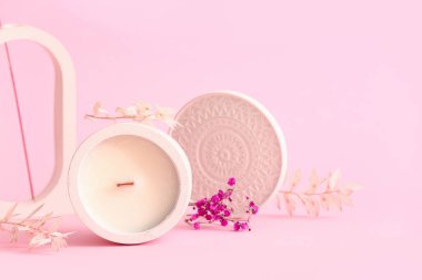 Elinde mum ve pembe arka planda dekoratif podyum olan tutucu